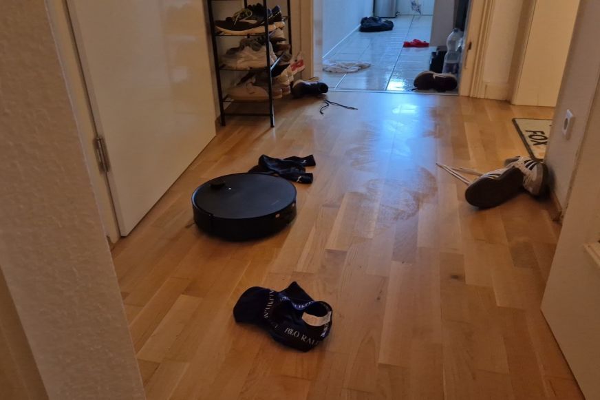 Roborock Saros 20 Flow fährt durch einen Hindernisparcours mit Schuhen und Kabeln